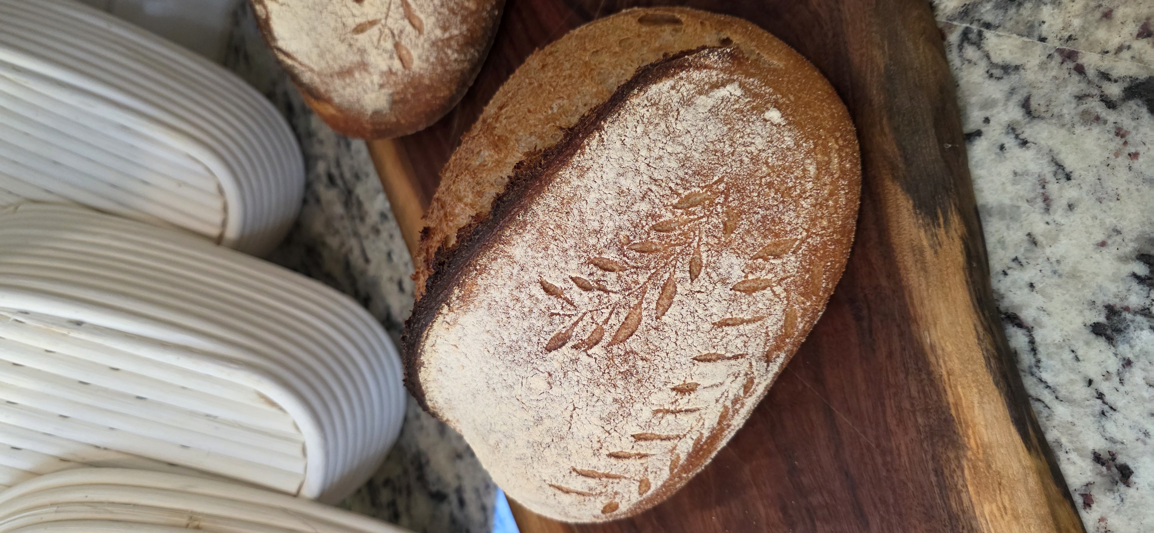 Decoratively scored sourdough loaves on a wooden board