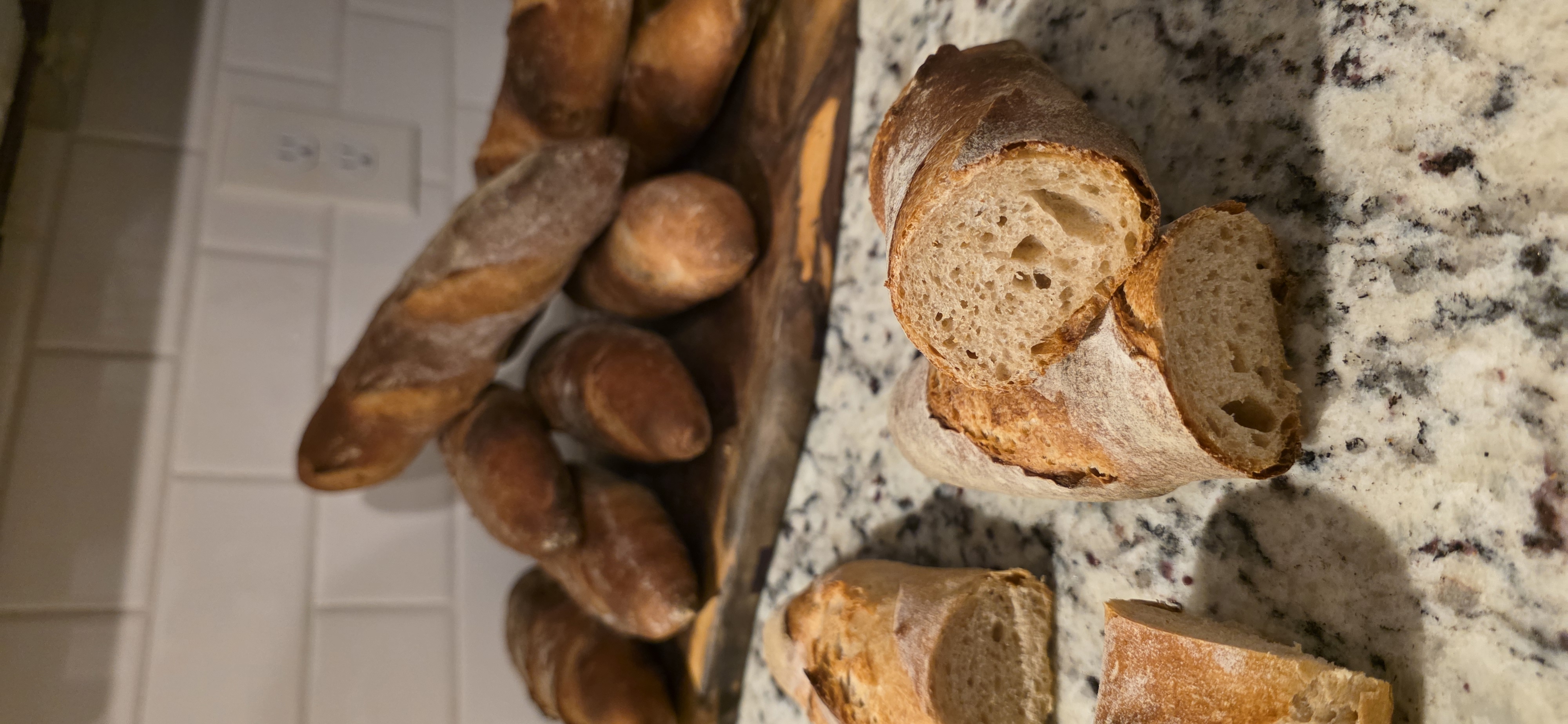 Rustic baguettes, including cut loaves showing their crumb