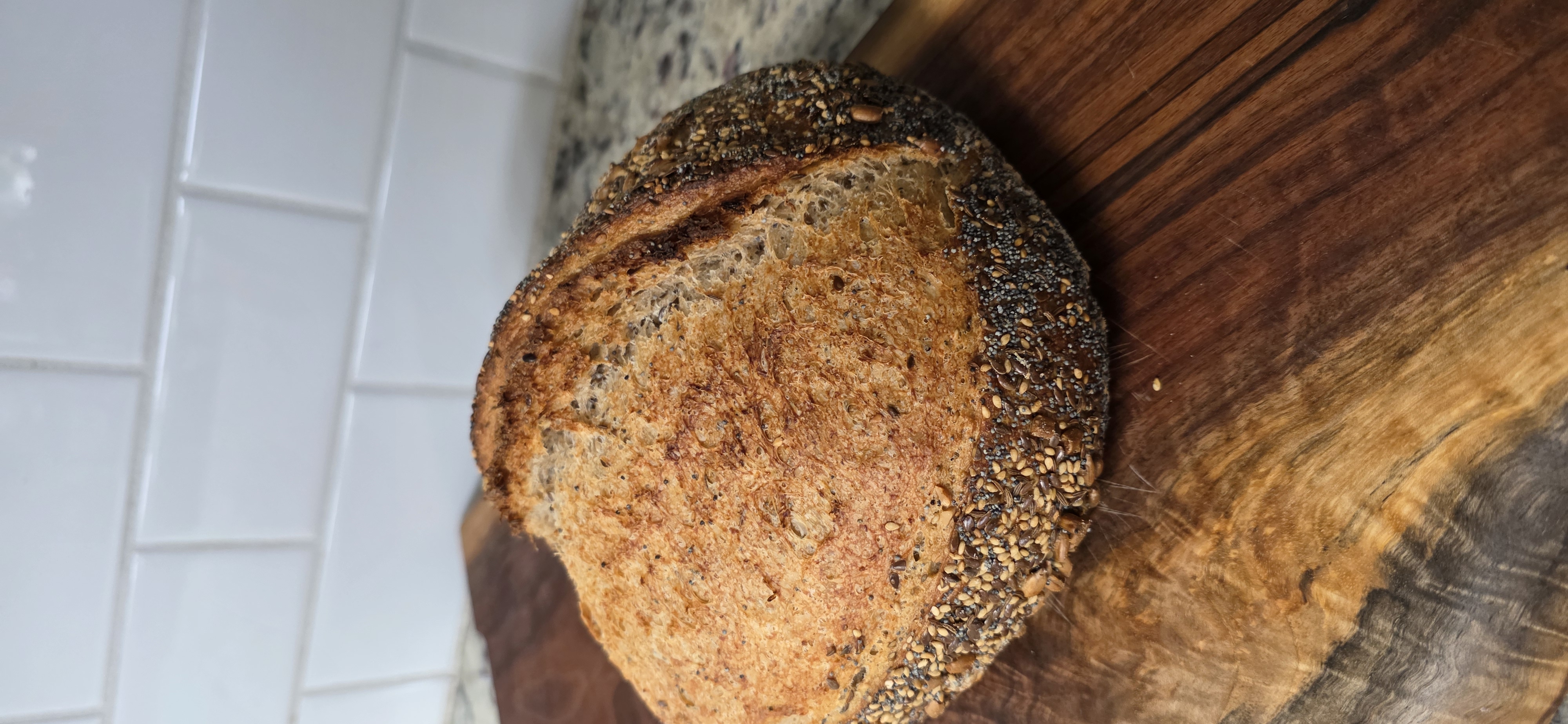 A round sourdough loaf coated with mixed seeds