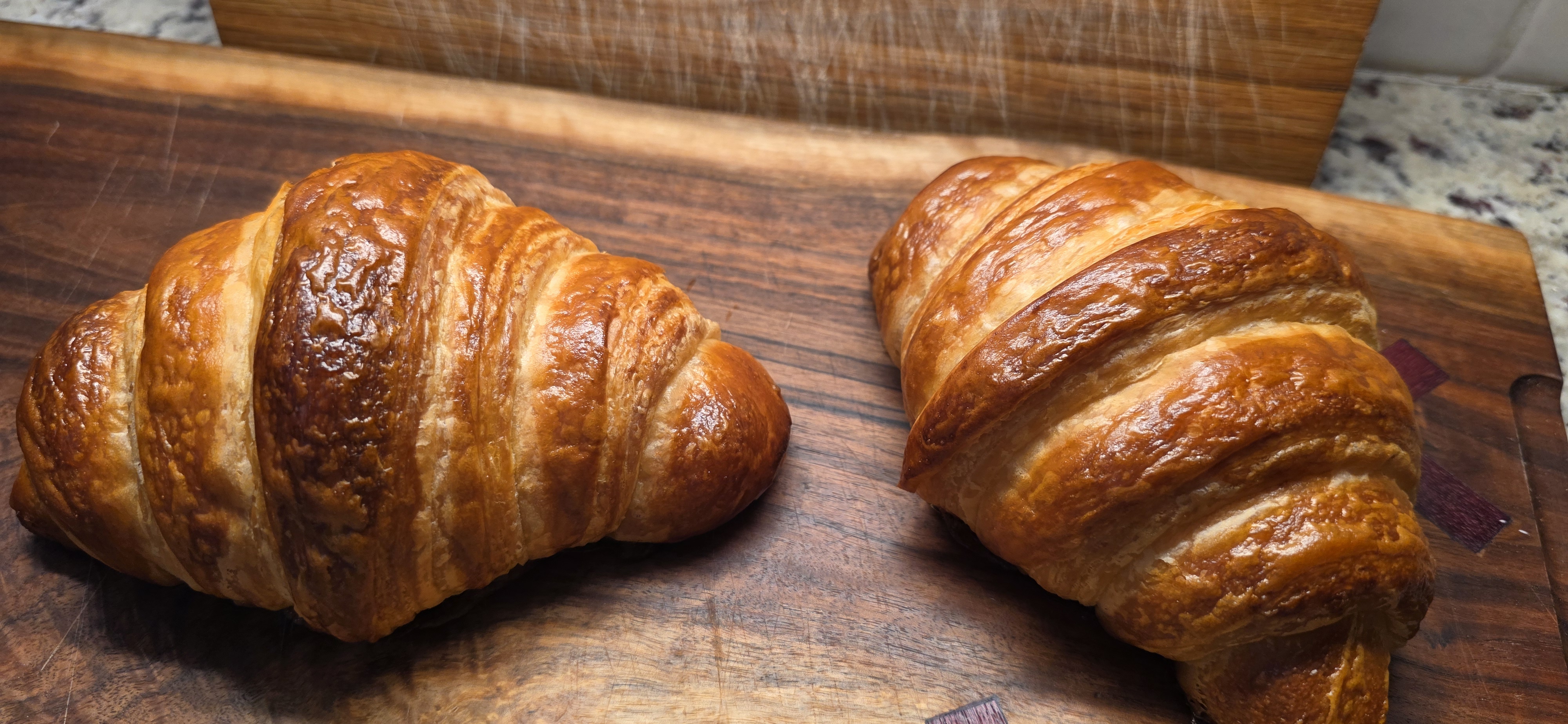Two golden croissants on a wooden board
